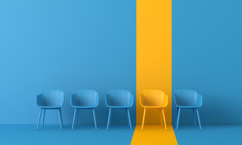 Yellow Chair amongst rows of blue chairs.