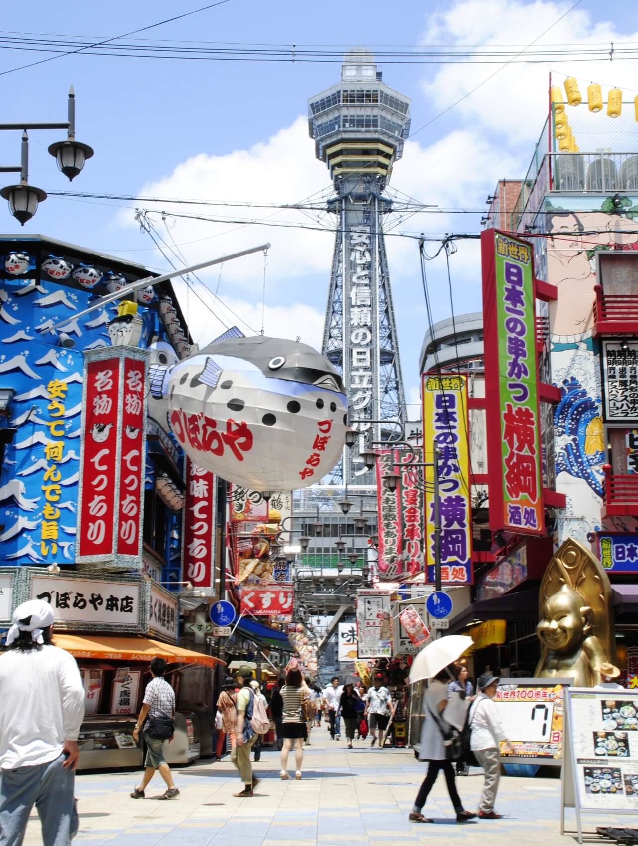 The street of Shinsekai district with colourful shop signs and Tsutenkaku Tower
